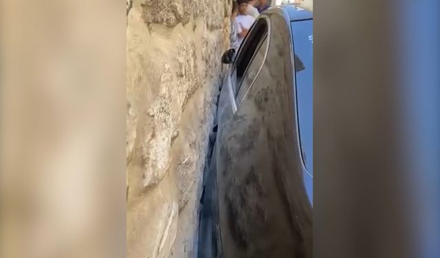Dar sokakta sıkışan otomobil güçlükle çıkarıldı